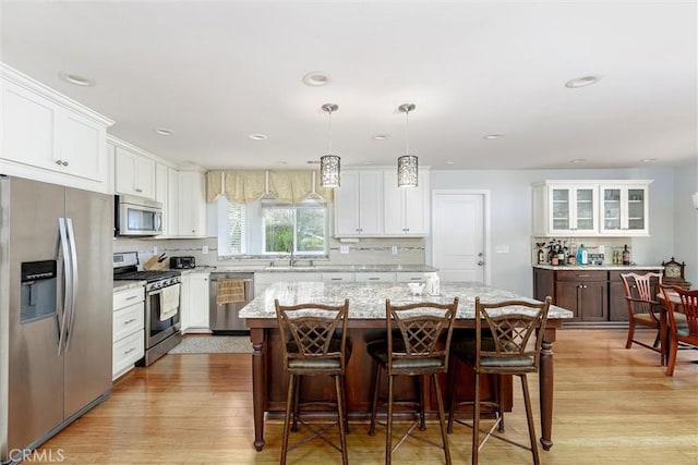 kitchen with a breakfast bar, pendant lighting, white cabinets, a center island, and stainless steel appliances