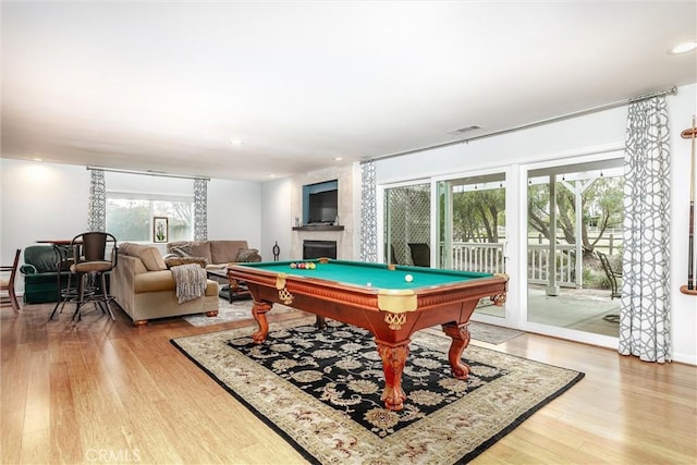 rec room featuring pool table, wood-type flooring, and a tiled fireplace