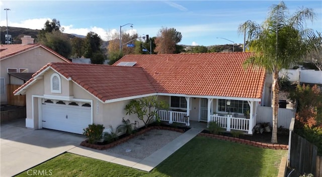 view of front of property featuring a porch, an attached garage, stucco siding, concrete driveway, and a tiled roof