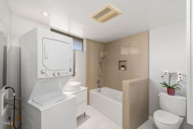 bathroom featuring vanity, tile patterned floors, toilet, and stacked washing maching and dryer