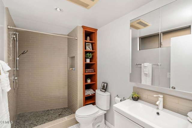 bathroom featuring a tile shower, backsplash, and toilet