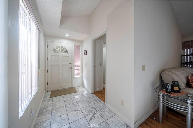 foyer entrance with lofted ceiling and a textured ceiling