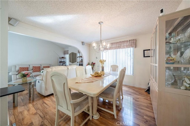 dining space featuring a chandelier, light hardwood / wood-style floors, and a textured ceiling