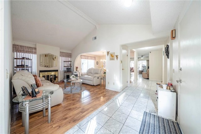 living room featuring beamed ceiling, ceiling fan, high vaulted ceiling, and light wood-type flooring