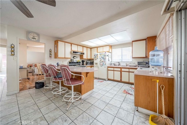 kitchen featuring range, a center island, white fridge with ice dispenser, a kitchen bar, and light tile patterned flooring