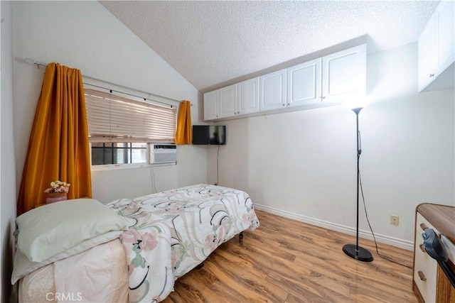 bedroom with cooling unit, lofted ceiling, a textured ceiling, and light wood-type flooring