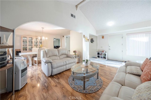 living room featuring beamed ceiling, high vaulted ceiling, an inviting chandelier, and light hardwood / wood-style flooring