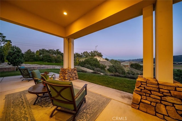 patio terrace at dusk featuring a lawn