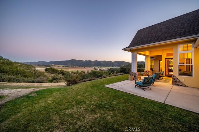 yard at dusk featuring an outdoor hangout area, a mountain view, and a patio