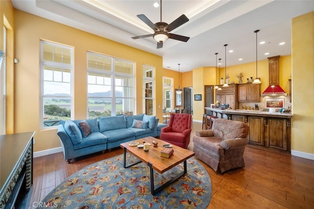 living room with dark hardwood / wood-style floors, a raised ceiling, and ceiling fan