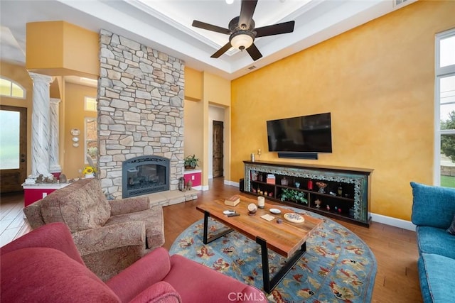 living room featuring ornate columns, dark hardwood / wood-style floors, ceiling fan, a fireplace, and a high ceiling