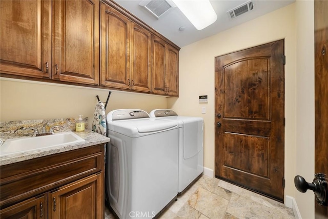 clothes washing area featuring cabinets, washer and dryer, and sink