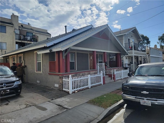 bungalow-style house with a shingled roof, a fenced front yard, stucco siding, crawl space, and covered porch