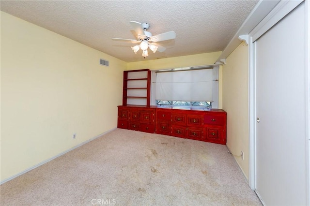 unfurnished bedroom featuring ceiling fan, light carpet, and a textured ceiling