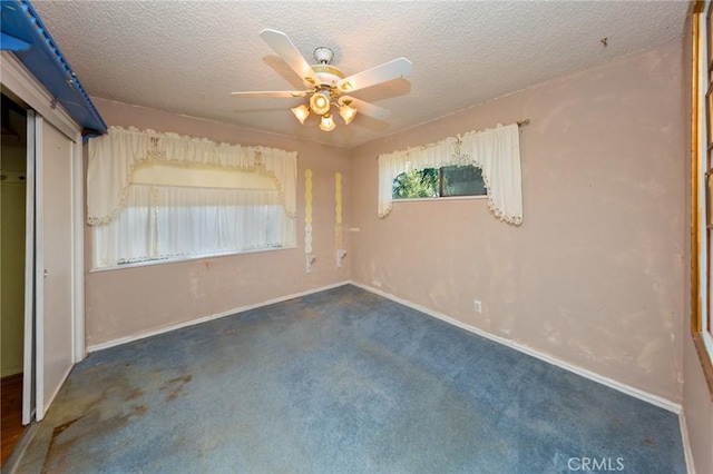 unfurnished bedroom with ceiling fan, a closet, a textured ceiling, and dark colored carpet