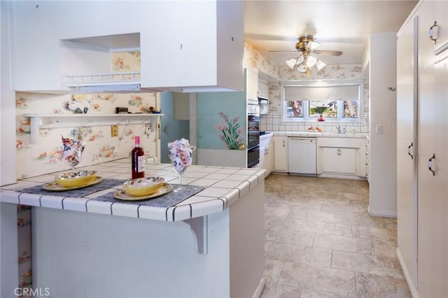 kitchen featuring white cabinetry, tasteful backsplash, tile countertops, dishwasher, and ceiling fan