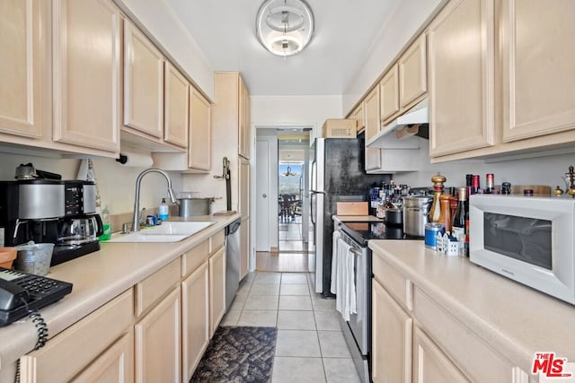 kitchen featuring stainless steel appliances, sink, light brown cabinets, and light tile patterned floors