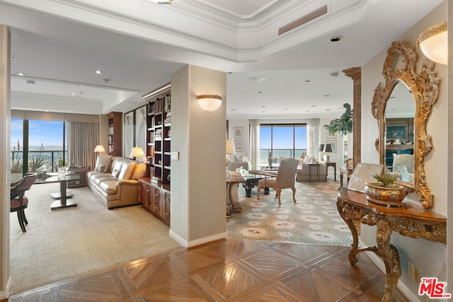 interior space with crown molding, a tray ceiling, and light parquet floors