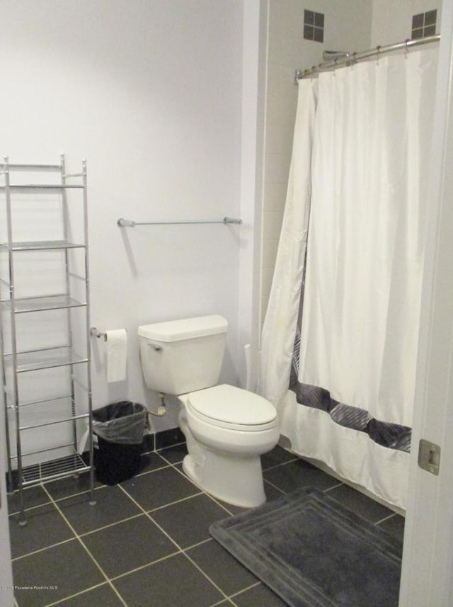 bathroom with walk in shower, toilet, and tile patterned flooring