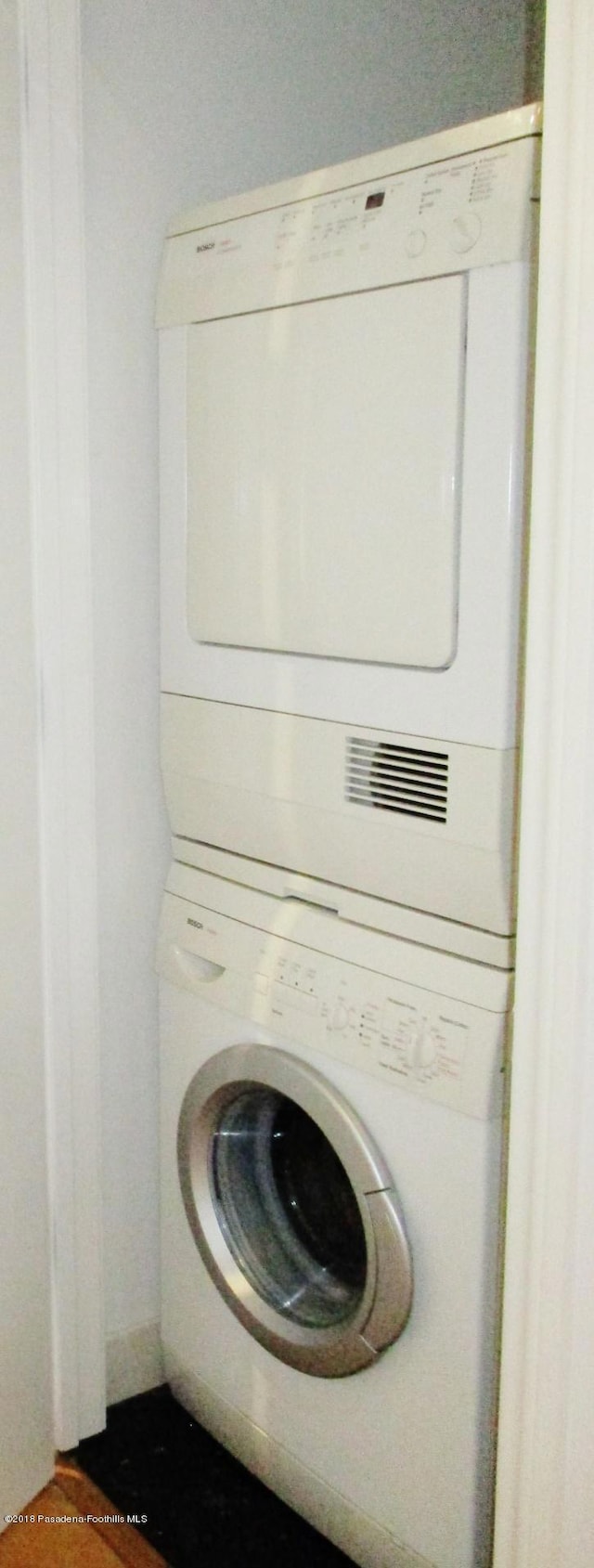 clothes washing area with stacked washer and clothes dryer