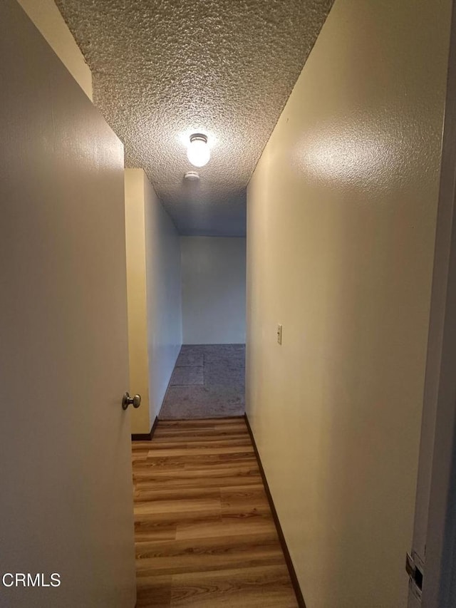 hallway featuring wood-type flooring and a textured ceiling