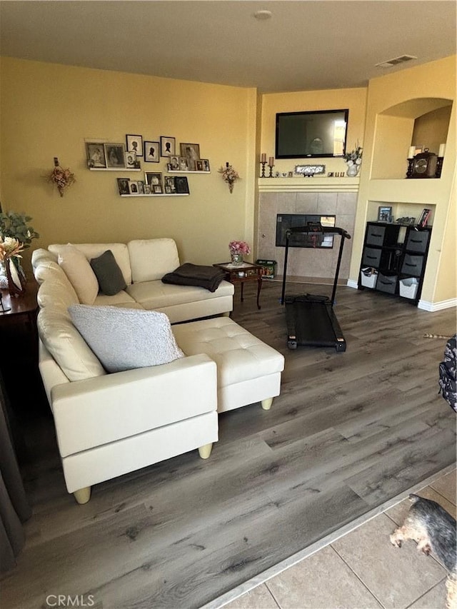 living room with a tile fireplace and hardwood / wood-style floors