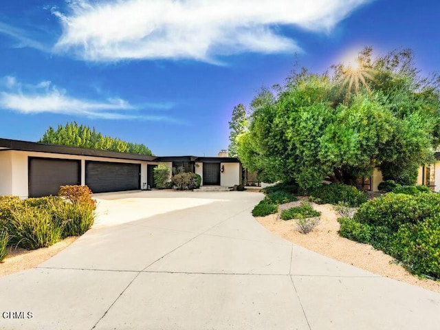 view of front of house featuring a garage, concrete driveway, and stucco siding