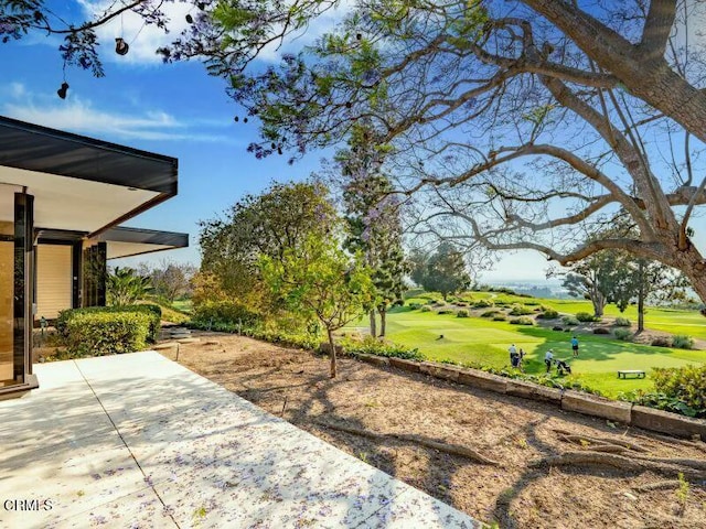 view of yard with view of golf course and a patio area