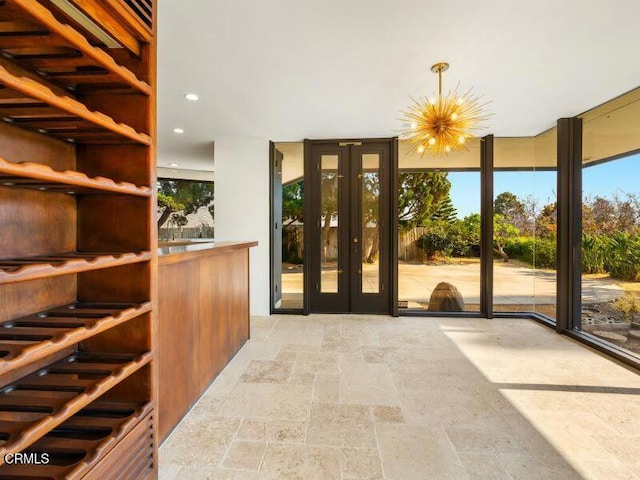 interior space with a chandelier, recessed lighting, french doors, a wall of windows, and stone tile flooring