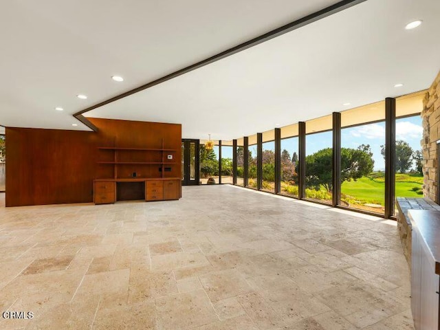 living area with stone finish flooring, floor to ceiling windows, recessed lighting, and wooden walls