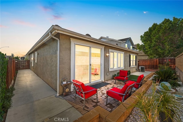 back house at dusk with central AC unit and a patio area