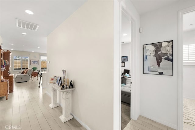 hall with a healthy amount of sunlight and light hardwood / wood-style flooring