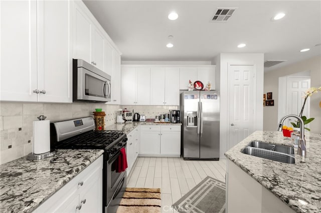 kitchen featuring white cabinetry, appliances with stainless steel finishes, light stone countertops, and sink