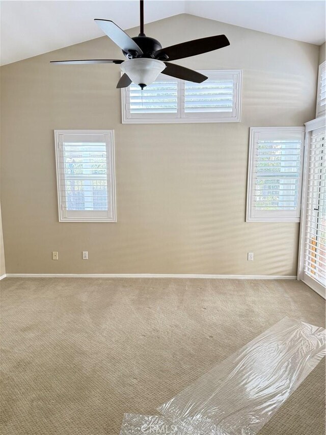 spare room with vaulted ceiling, light colored carpet, and ceiling fan