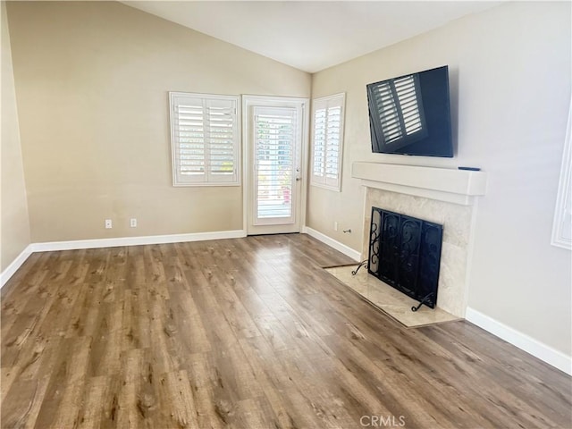 unfurnished living room with lofted ceiling, hardwood / wood-style flooring, and a high end fireplace