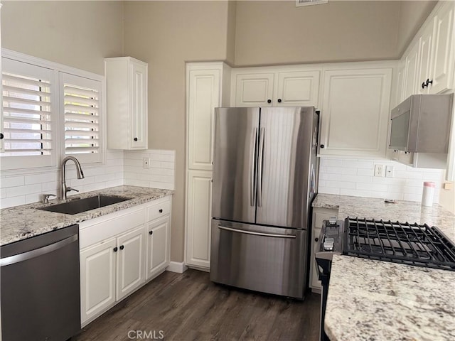 kitchen featuring light stone counters, sink, stainless steel appliances, and white cabinets