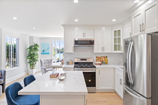 kitchen with light stone counters, appliances with stainless steel finishes, a breakfast bar, and white cabinets