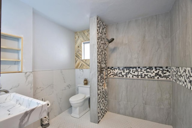 bathroom with a tile shower, tile walls, and toilet