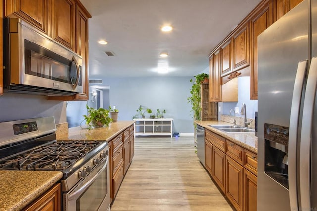 kitchen featuring stainless steel appliances, light stone countertops, sink, and light hardwood / wood-style floors