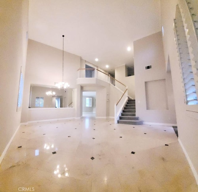 unfurnished living room featuring a towering ceiling and a notable chandelier