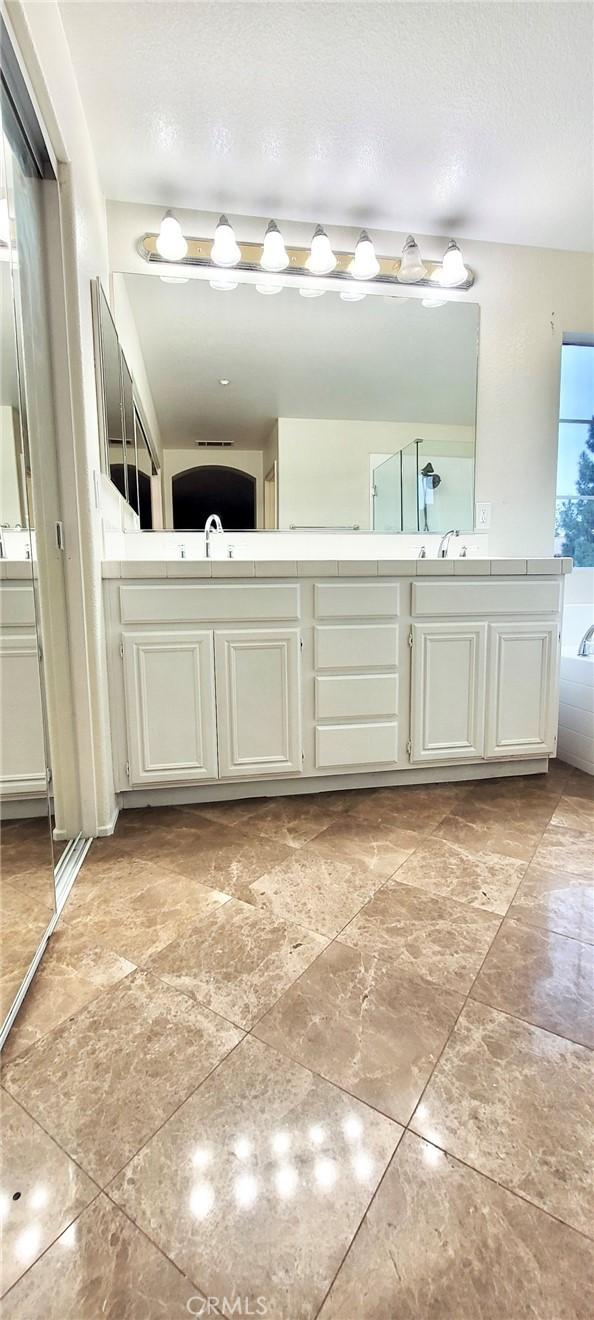 bathroom with vanity, a textured ceiling, and a washtub