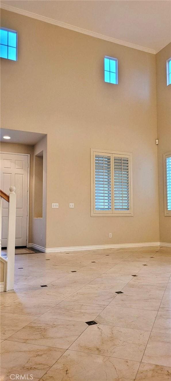 spare room featuring a high ceiling, ornamental molding, and a healthy amount of sunlight