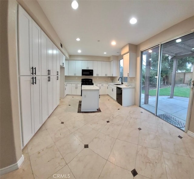 kitchen with sink, black appliances, a center island, and white cabinets