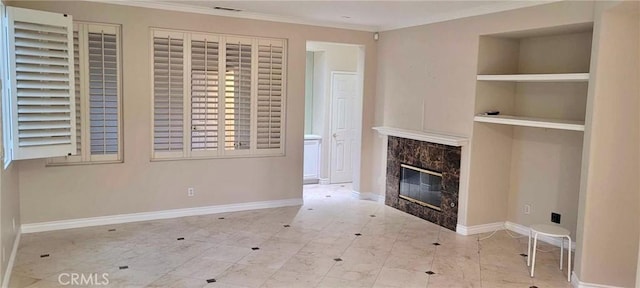 unfurnished living room featuring built in shelves, a premium fireplace, and crown molding