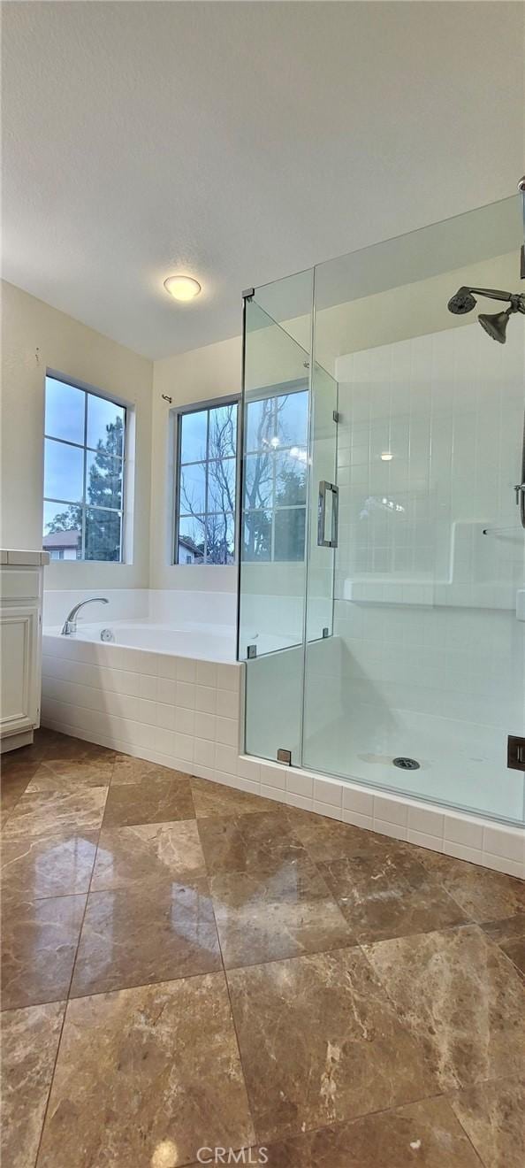 bathroom with ceiling fan, shower with separate bathtub, and a textured ceiling