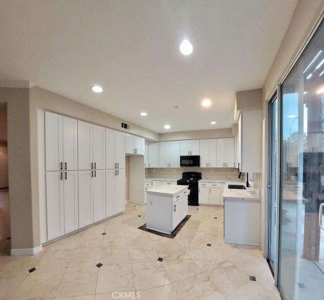 kitchen featuring white cabinetry, a kitchen island, sink, and black appliances