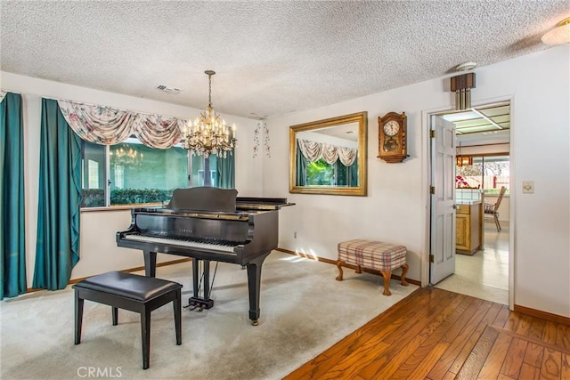 misc room with an inviting chandelier, a textured ceiling, and light wood-type flooring