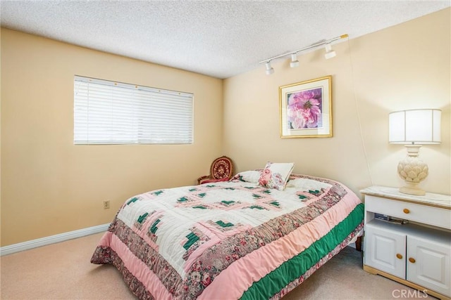 bedroom with light colored carpet, rail lighting, and a textured ceiling