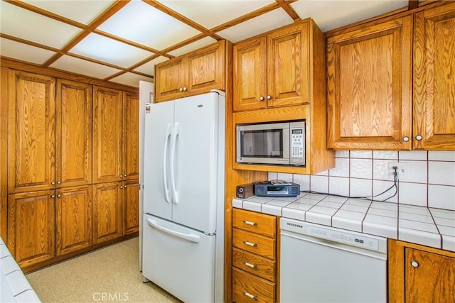 kitchen featuring tasteful backsplash, tile countertops, and white appliances