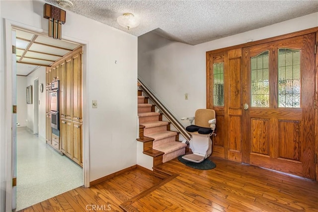 foyer entrance with a textured ceiling and light hardwood / wood-style flooring